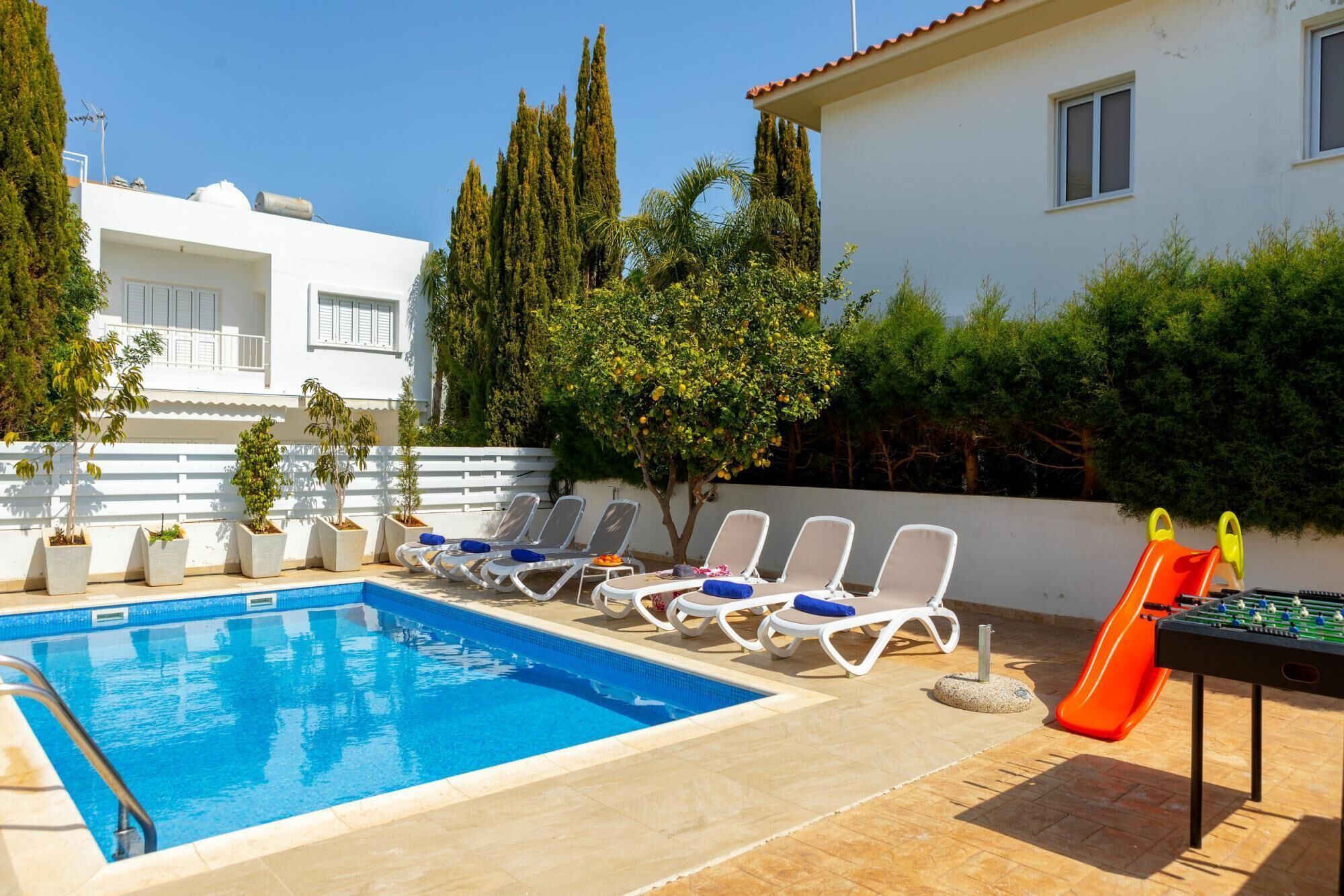 A swimming pool with lounge chairs and a foosball table.