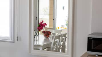A kitchen with white cabinets, a white countertop, and a window with a view of the outdoors.
