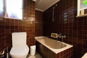 A bathroom with a toilet, sink, and bathtub, all with metallic fixtures.