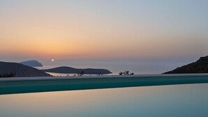 A serene sunset over a calm sea with distant landforms and a clear sky. - Spacious 6 Bdrm Stone Villa With Pool (Serifos)