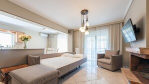A modern hotel room with a bed, a sofa, a TV, and a fireplace. - Luxury and Spacious apt for 8 Guests New Features April 2025 (Alimos)