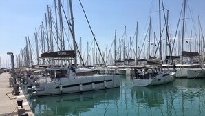 A marina with multiple boats docked, a concrete walkway, and a building with a sign. - Luxury and Spacious apt for 8 Guests New Features April 2025 (Alimos)