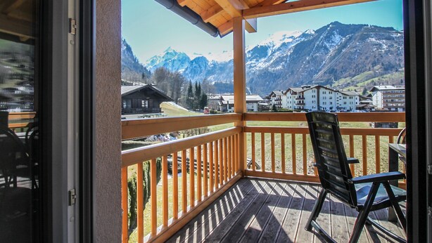A wooden deck with a view of snow-capped mountains and buildings. - Tauern Relax Lodges - Penthouse (Kaprun)