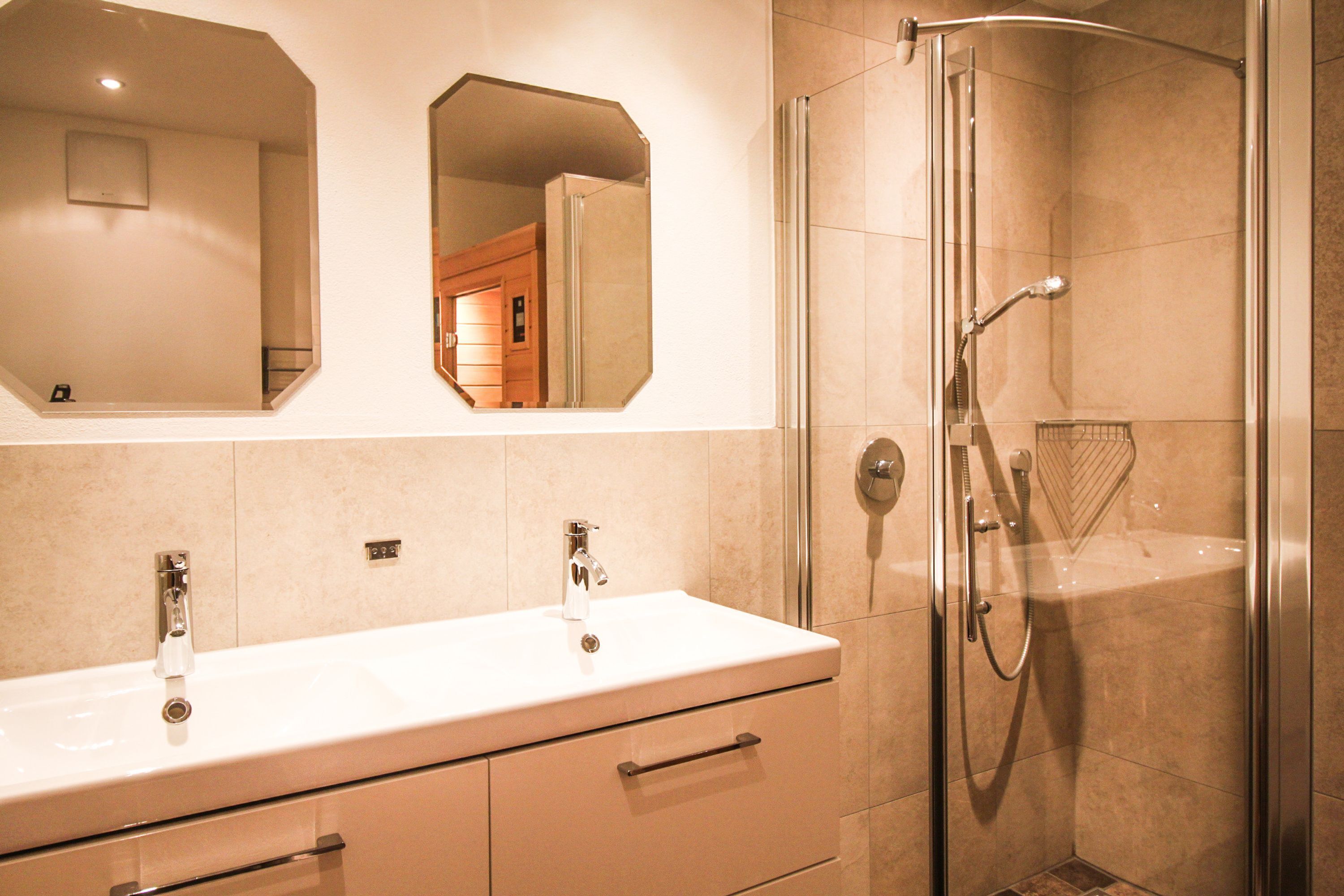 Une salle de bain avec deux vasques, une douche et deux miroirs.