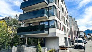 Ein modernes mehrstöckiges Gebäude mit Balkonen, großen Fenstern und blauem Himmel.