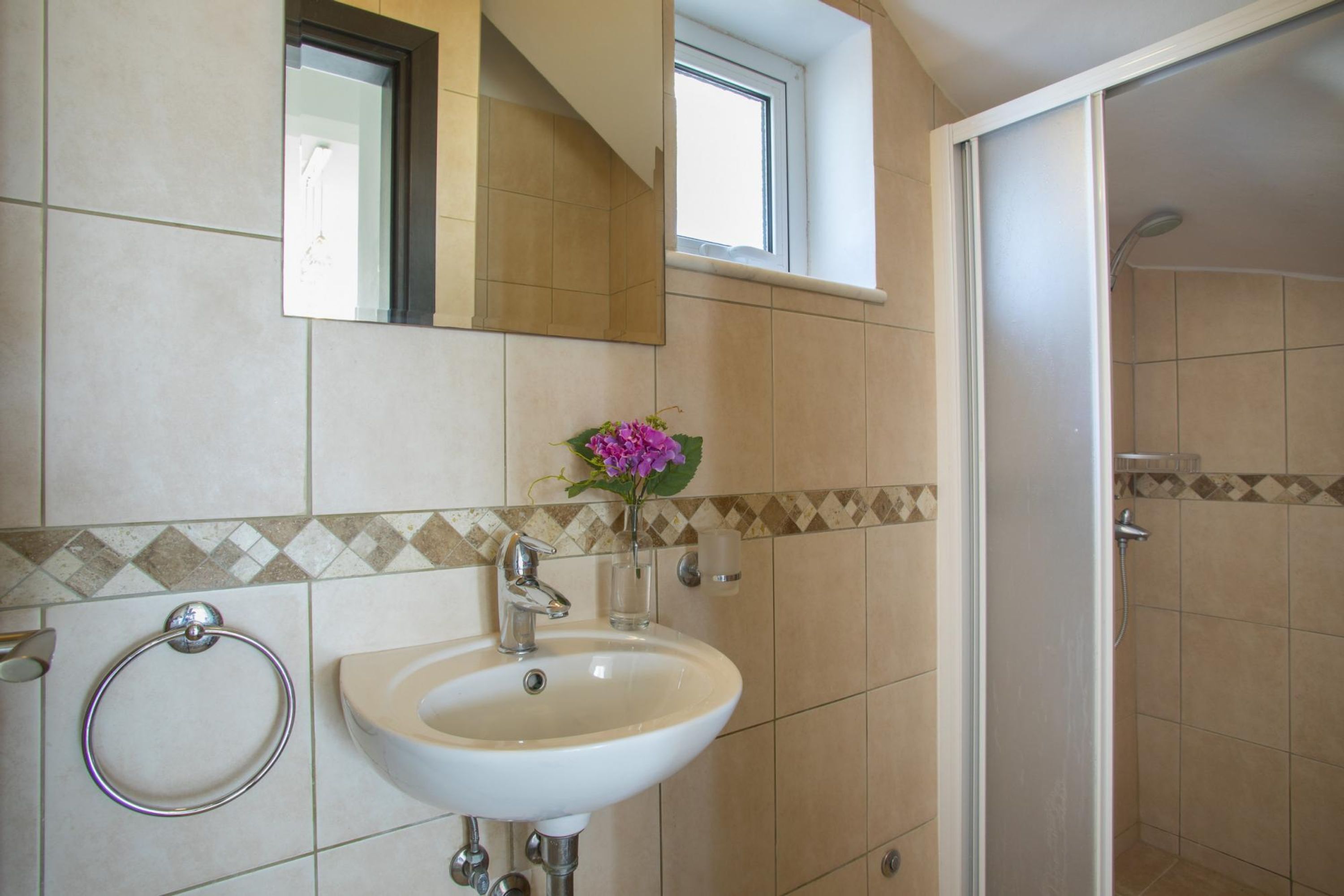 Een badkamer met een wastafel, spiegel en raam.