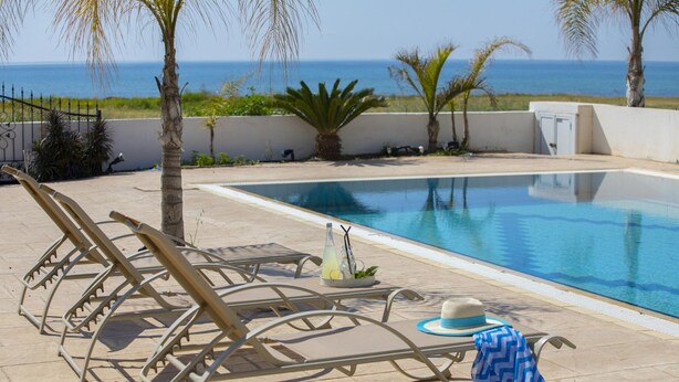 Zona de piscina con sillas de descanso, un sombrero y una toalla.
