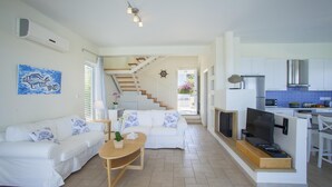 A modern living room with a sofa, a coffee table, and a TV. There is a staircase leading to an upper level. - Villa Melissa Selana (Paralimni)