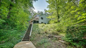 A wooden staircase leading to a house surrounded by dense greenery. - Maryland Vacation Rental w/ Private Pool & Dock (Lusby)