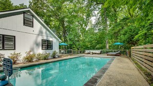 A swimming pool with a wooden deck, a white building with windows, and a wooden fence. - Maryland Vacation Rental w/ Private Pool & Dock (Lusby)