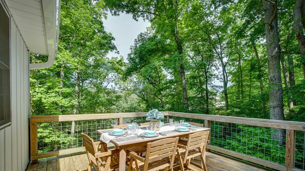 A wooden deck with a table set for dining, surrounded by trees. - Maryland Vacation Rental w/ Private Pool & Dock (Lusby)