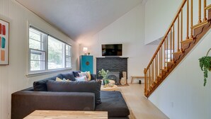 A living room with a dark sofa, wooden coffee table, and a fireplace. - Maryland Vacation Rental w/ Private Pool & Dock (Lusby)