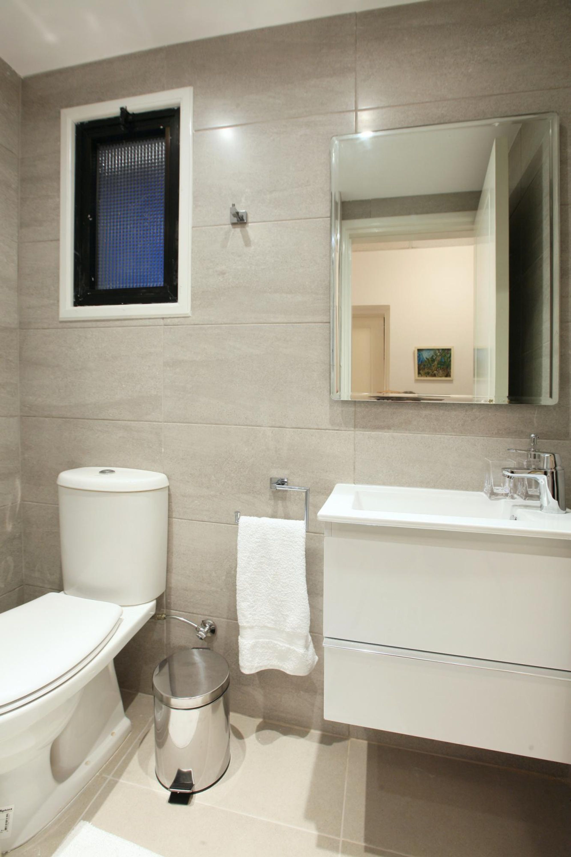 Een moderne badkamer met toilet, wastafel en spiegel.