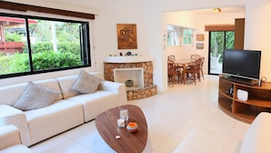 Uma sala de estar moderna com sofá, mesa de centro, lareira, área de jantar e TV.