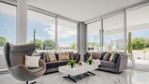 Ein modernes Wohnzimmer mit einem grauen Sofa, einem grauen Sessel und einem weißen Couchtisch mit Pflanzen.
