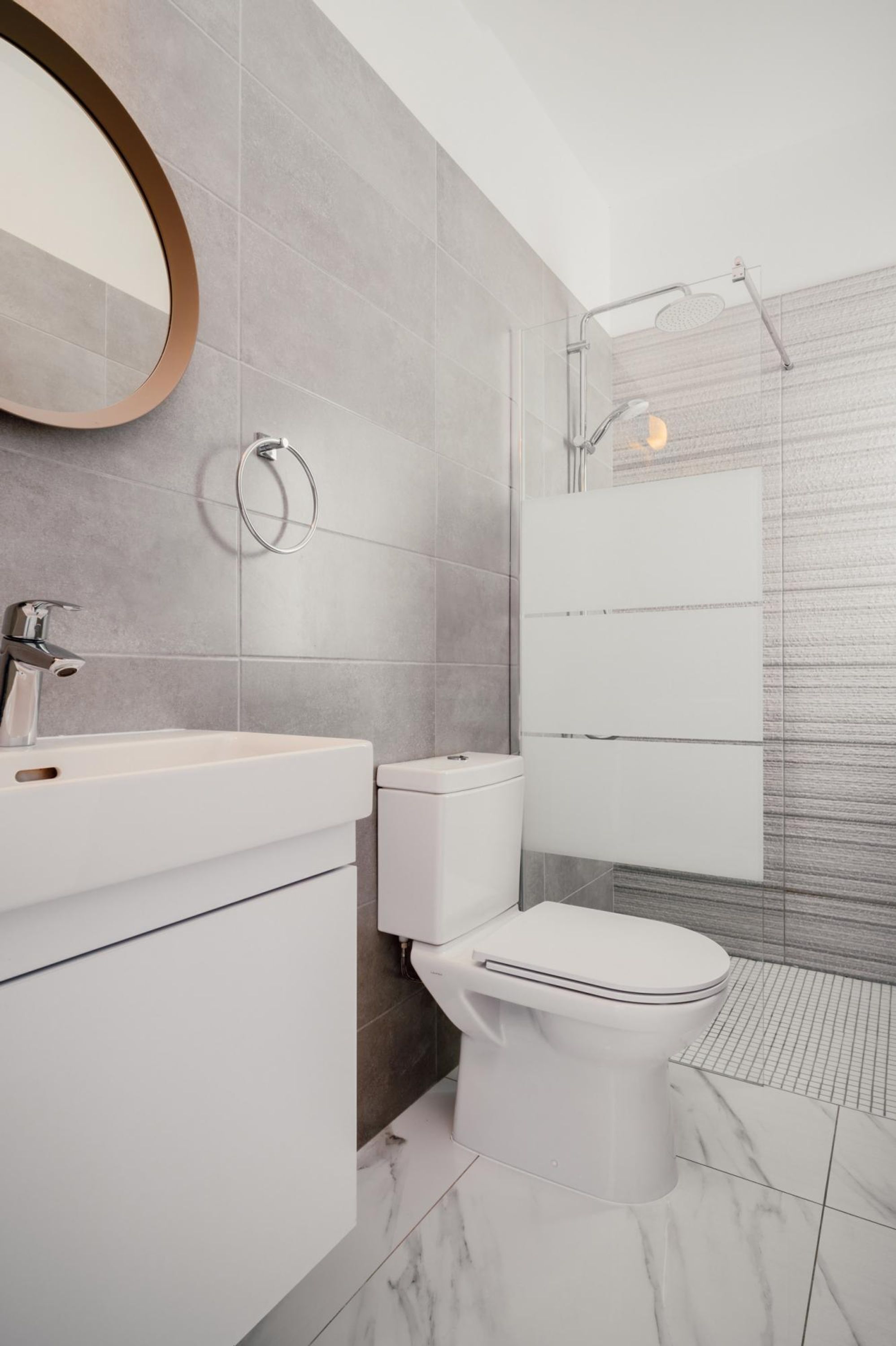 Une salle de bain moderne avec un lavabo, des toilettes et une douche, le tout de couleur blanche.