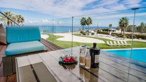 Un balcón con una mesa de vidrio, un sofá azul y vistas a la playa y al océano.