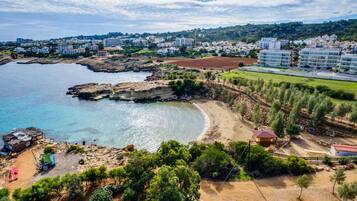 A coastal town with a beach, rocky shoreline, and residential buildings.