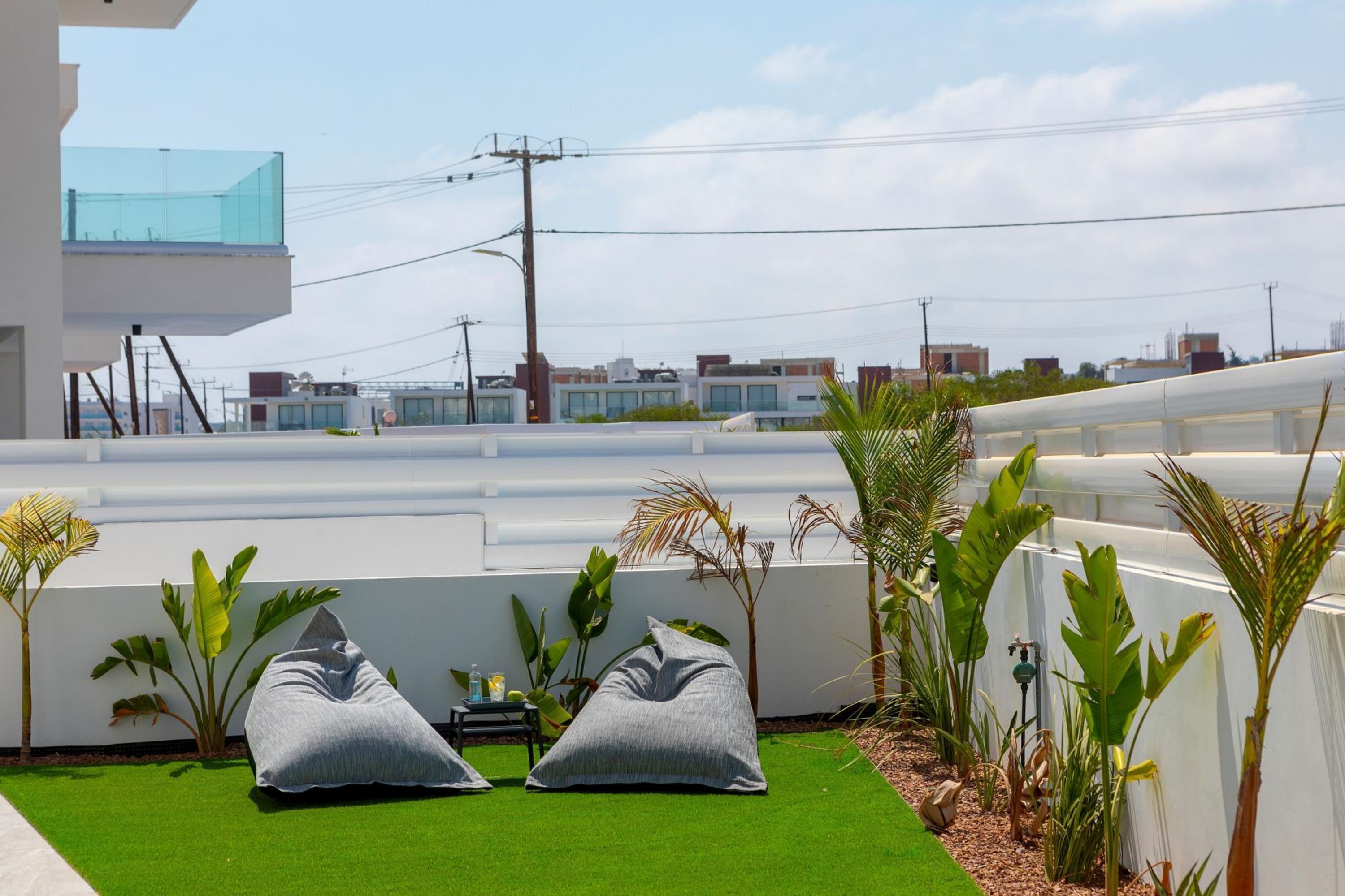 A rooftop garden with artificial grass, two bean bags, and various tropical plants.