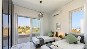 A modern bedroom with two beds, a large window, and a view of the city. - Protaras Sol e Mar Villa 3 (Paralimni)