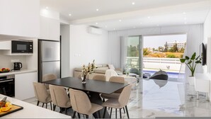A modern kitchen with a dining area, a sofa, and a view of a pool. - Protaras Sol e Mar Villa 3 (Paralimni)
