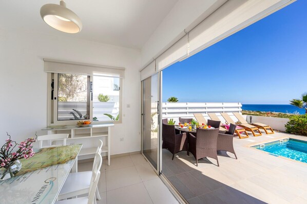 A modern apartment with a balcony, a dining area, and a pool. - Protaras Artisan Seafront Villa 1 (Paralimni)