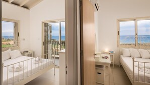 Een kamer met balkon, een bed, bureau en uitzicht op zee.