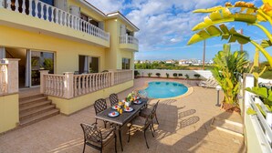 A two-story building with a swimming pool, outdoor seating, and a balcony. - Protaras Posidon By The Sea (Paralimni)