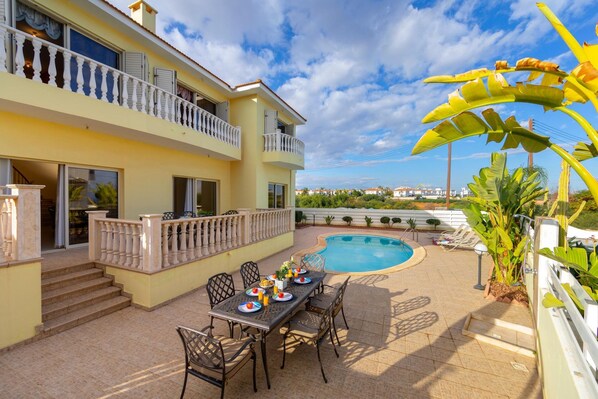 A two-story building with a swimming pool, outdoor seating, and a balcony. - Protaras Posidon By The Sea (Paralimni)