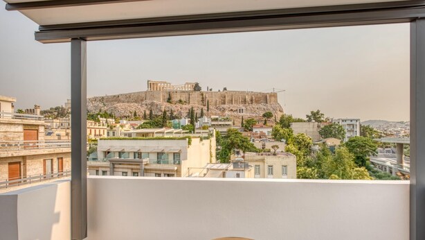 A balcony with two round tables and a view of ancient ruins in the background. - Lux Deck Roof Apt at the Foothills of Acropolis w Breathtaking View (Athens)