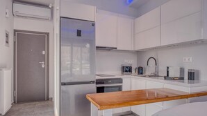 A compact kitchen with a built-in refrigerator, a stove, a coffee maker, and a microwave. - Lux Deck Roof Apt at the Foothills of Acropolis w Breathtaking View (Athens)