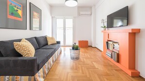 A living room with a sofa, a fireplace, a television, and a door leading to a balcony. - New Relaxed Central Apartment Walk Everywhere (Athens)