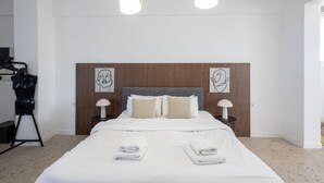A modern hotel room with a large bed, wooden headboard, two bedside tables with lamps, and artwork on the walls. - Loft at Historical Center of Athens w Acropolis View (Athens)