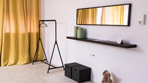 A room with a black hanger stand, a black storage unit, a green vase, a yellow bust sculpture, and a framed mirror on a wall. - Loft at Historical Center of Athens w Acropolis View (Athens)