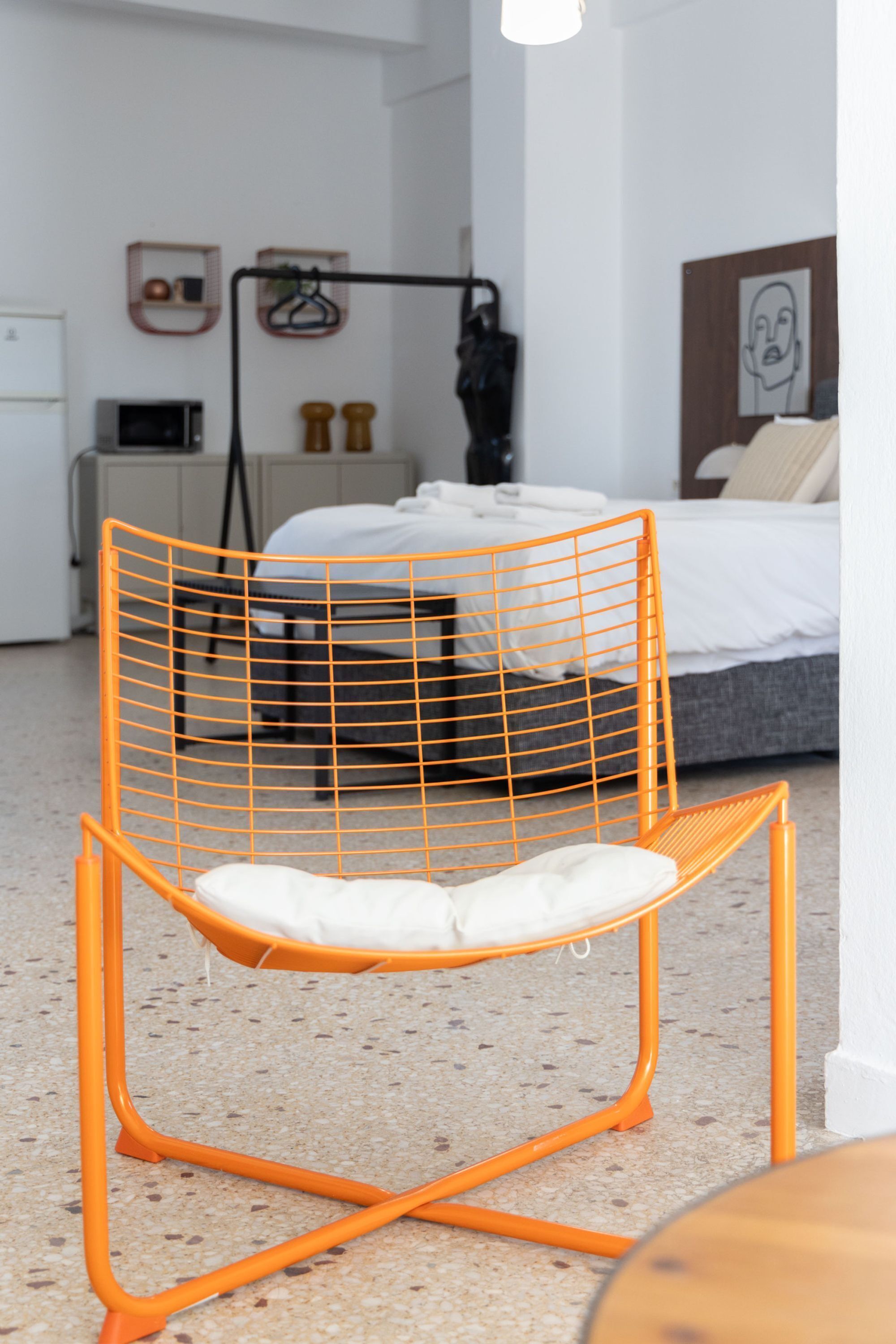 Habitació moderna amb un llit, una cadira, un microones i una taula petita.