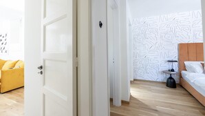 A bedroom with a bed, a bedside table, a lamp, and a patterned wall. - Paradise Suite With Jacuzzi Acropolis View (Athens)