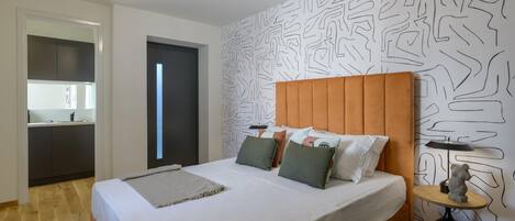 A modern bedroom with a large bed, a wooden headboard, and a patterned wall.