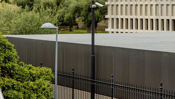 Un bâtiment moderne avec une façade en béton, de grandes fenêtres et une clôture en métal.