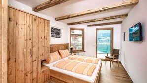 Une chambre à coucher avec un lit en bois, une armoire en bois et une grande fenêtre donnant sur un paysage enneigé.
