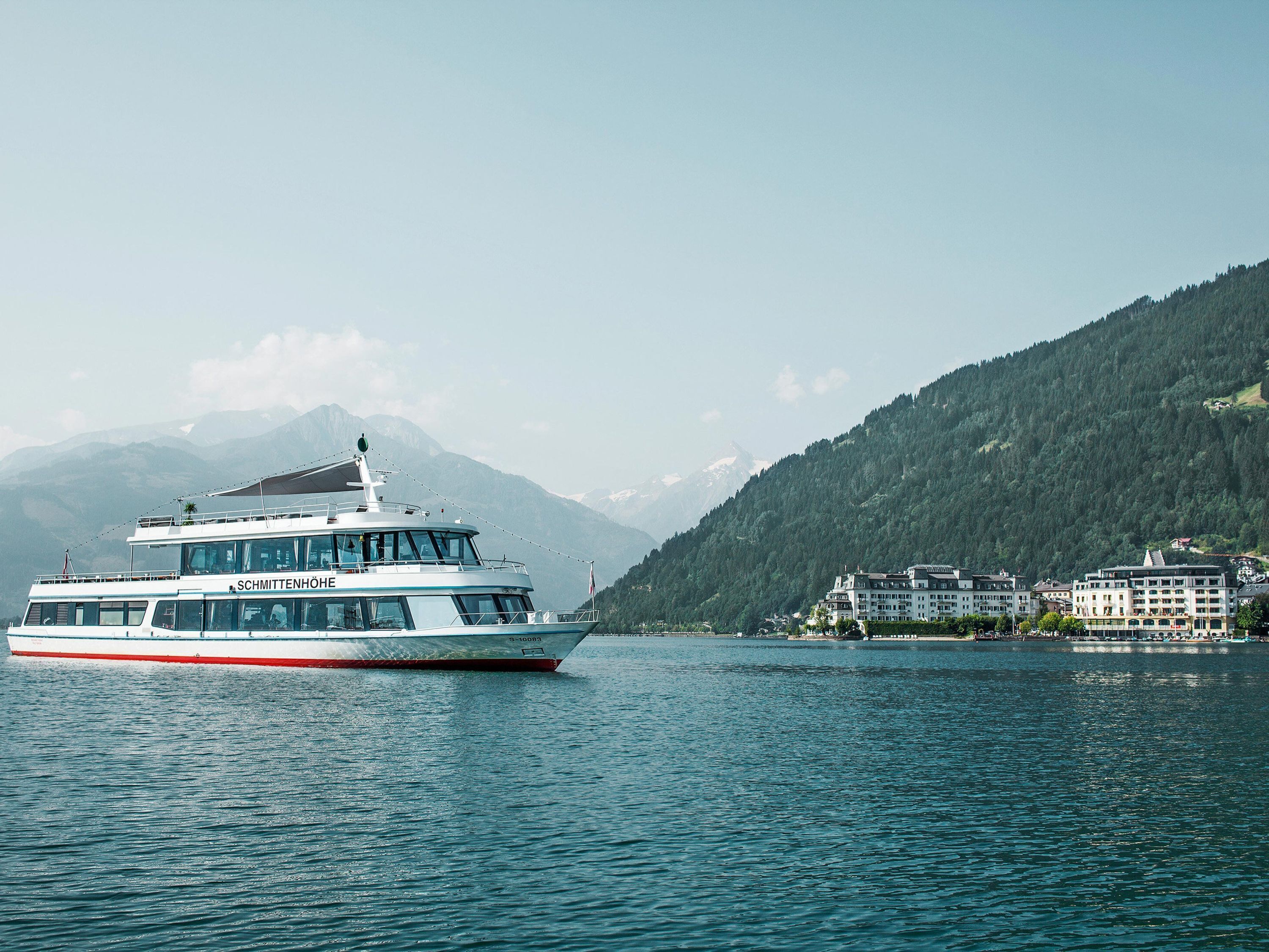 A boat named SCHMITTENHÖHE on a lake with a mountainous backdrop.