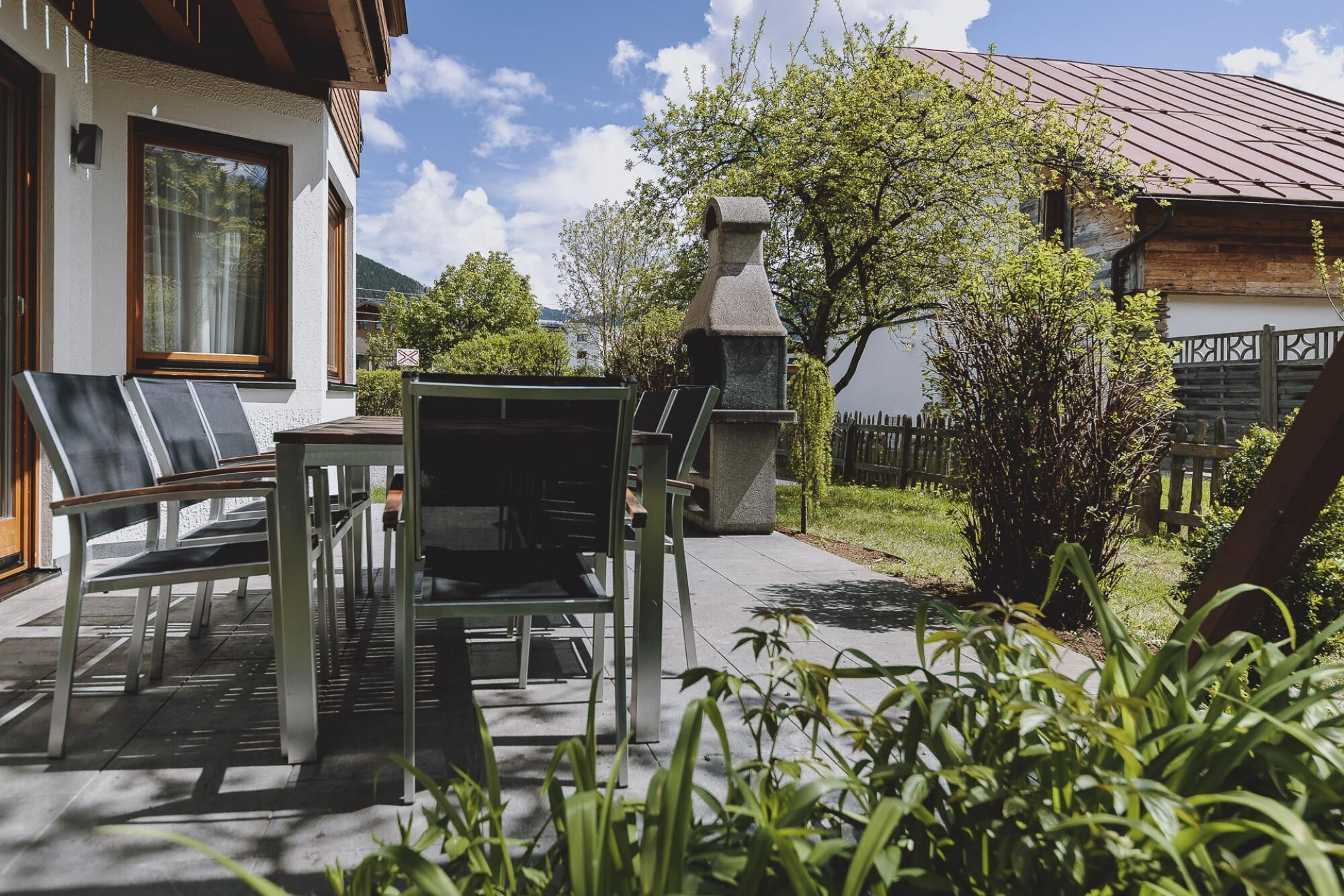 A patio with outdoor seating, a stone chimney, and a view of a mountain.