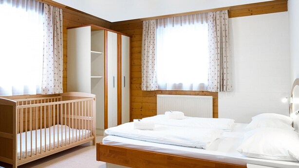A bedroom with a wooden bed, a crib, and a walk-in closet.