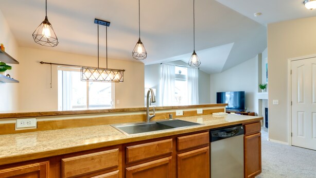 Una cucina moderna con mobili in legno, lavello in acciaio inossidabile e illuminazione a sospensione.
