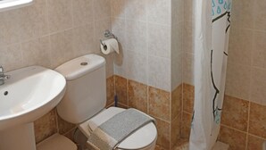 A bathroom with a toilet, sink, and shower curtain.