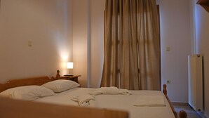A hotel room with a wooden bed, a nightstand with a lamp, and a radiator.
