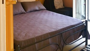 Un dormitorio con una cama, un cuadro de un cielo nocturno, un equipo de aire acondicionado y una ventana con cortinas.