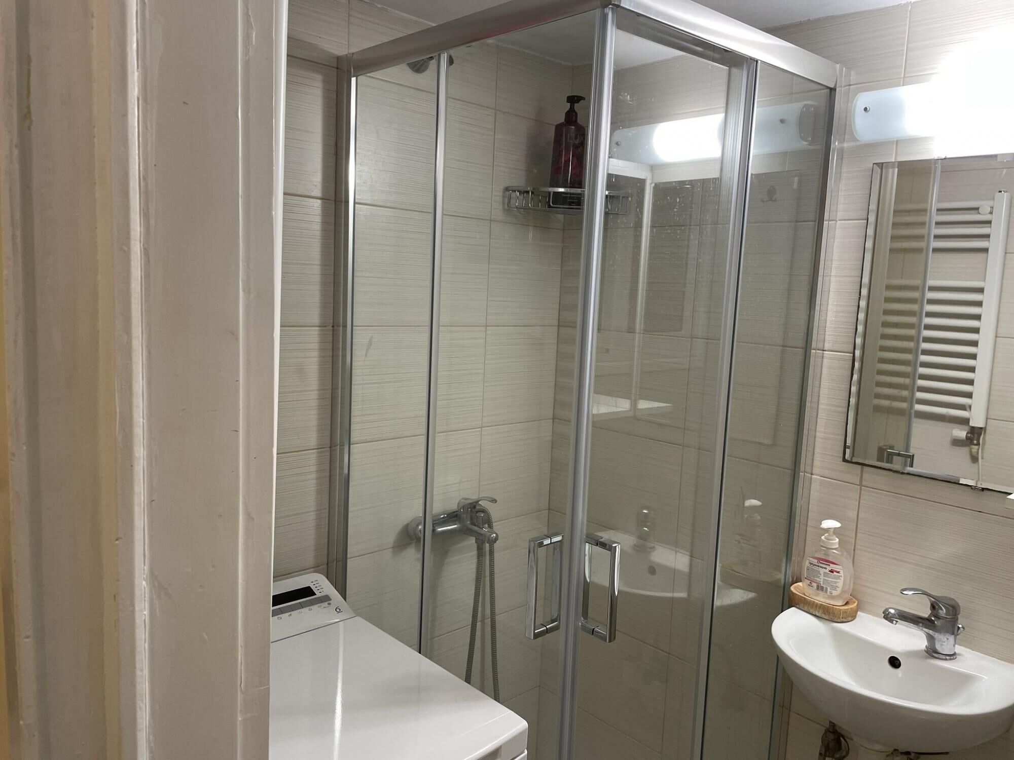 A modern bathroom with a glass-enclosed shower, a white sink, and a mirror above the sink.