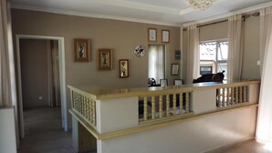A spacious living area with a wooden balcony, a chandelier, and a view of the outside.