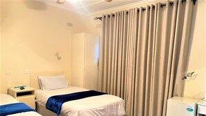 A hotel room with two beds, a wardrobe, a desk, and a mini-fridge. - Twin Room in Hillside - 2087 (Bulawayo)