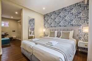 A hotel room with a large bed, a bedside table, a mirror, and a bathroom visible in the background. - Quinta da Tia Briosa Casa da M e I by Homie (Ponta do Sol)